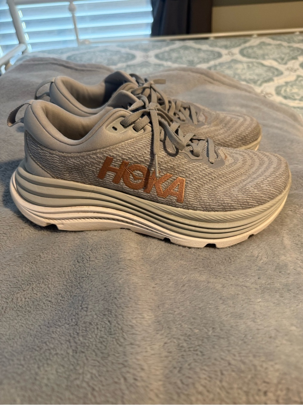 Hoka women’s Light Gray Gaviota 5 Sneakers with Gold Logo.